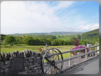 a stone fence with a stonewheel next to a stone wall at Golygfar Mynydd in Ystrad Meurig