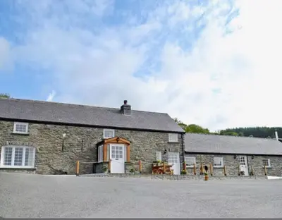 an old stone building with a white door at Golygfar Mynydd in Ystrad Meurig