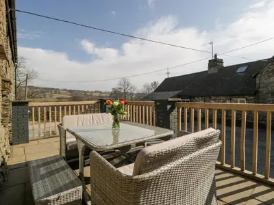 a patio with a table and chairs on a balcony at White Haywood Barn in Hereford
