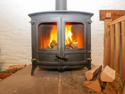 a gray stove with fire inside of it at White Haywood Barn in Hereford