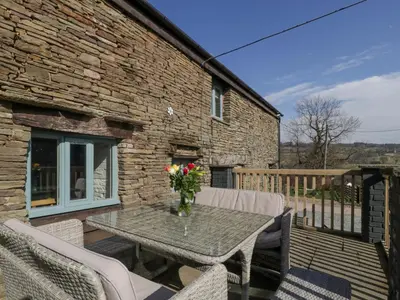 a patio with a table and chairs and a brick building at White Haywood Barn in Hereford