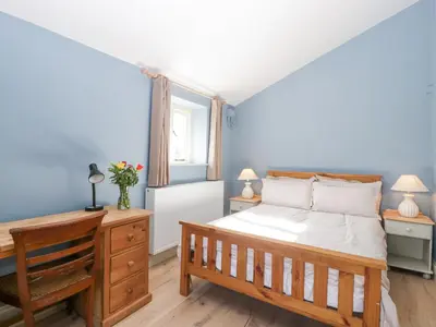 a bedroom with a bed and a desk with two lamps at White Haywood Barn in Hereford