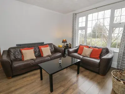 a living room with a leather couch and a table at Tan Y Fron in Dyffryn