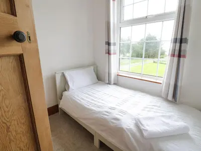 a small bedroom with a bed and a window at Tan Y Fron in Dyffryn
