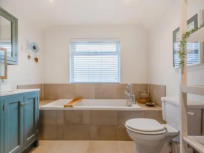 a bathroom with a tub and a toilet and a sink at Isfryn in Llanbedr