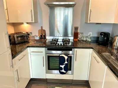 a kitchen with white cabinets and an oven in it at Luxury 2 bedroom town apartment in Aberystwyth