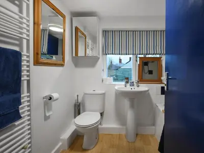 a white bathroom with a toilet and a sink at Sheldon Cottage in Bishops Castle