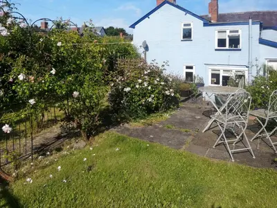a garden with a table and chairs and a house at Sheldon Cottage in Bishops Castle