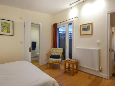 a bedroom with a bed and a chair and a window at Sheldon Cottage in Bishops Castle