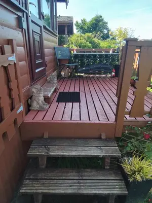 a deck with a bench and a chair on a house at Hamishs log cabin in Trawsfynydd