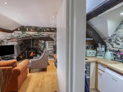 a kitchen and living room with a stone fireplace at Top Cottage Barmouth in Barmouth