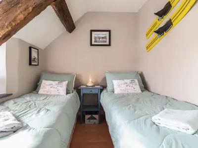 two twin beds in a room with a table at Top Cottage Barmouth in Barmouth