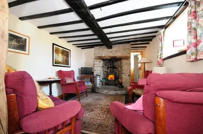 a living room with red chairs and a fireplace at Character cottage with spectacular views in Church Stoke