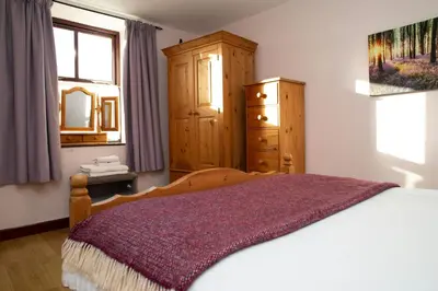 a bedroom with a bed and a dresser and a window at Tan-yr-Onnen Llangrannog in New Quay