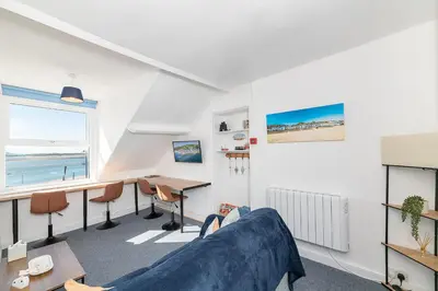 a living room with a blue couch and a desk at Aberdovey Sea View Apartment in Aberdyfi