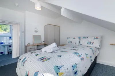 a white bedroom with a bed and a sink at Aberdovey Sea View Apartment in Aberdyfi
