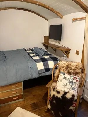 a bedroom with a bed and a chair and a tv at the railway carraige in Three Cocks Junction