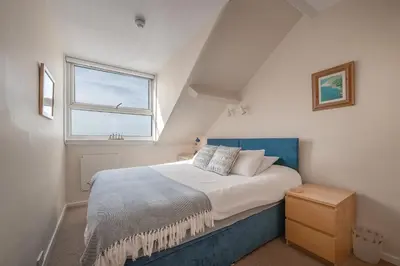 a bedroom with a bed with a blue headboard and a window at Beach Front flat in Aberdovey in Aberdyfi
