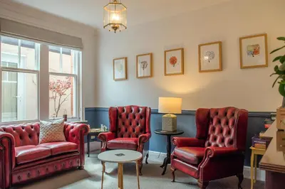 a living room with red chairs and a table at Mynd House in Church Stretton