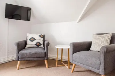 a living room with two chairs and a tv at Mynd House in Church Stretton
