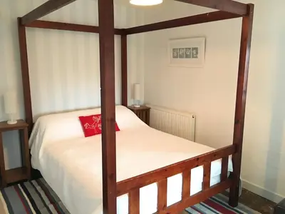 a bedroom with a wooden four poster bed at Secluded farmhouse with views in Cwrt-newydd
