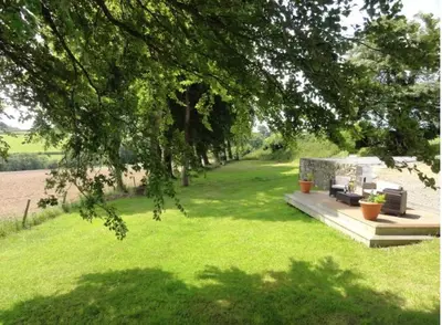 a garden with a bench and chairs under a tree at Secluded farmhouse with views in Cwrt-newydd