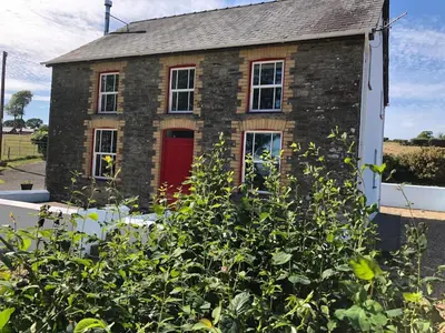 an old brick house with a red door at Secluded farmhouse with views in Cwrt-newydd