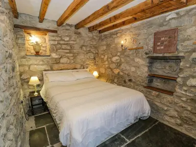 a bedroom with a bed in a stone wall at Ysgubor in Machynlleth