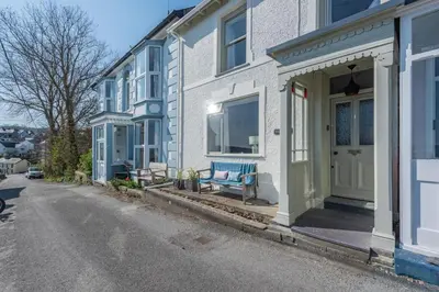 a white house with a blue bench on a street at 2 Bed in New Quay oc-h30586 in New Quay