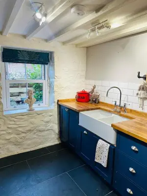a kitchen with blue cabinets and a sink and a window at Little Cottage, Llwyngwril in Llwyngwril