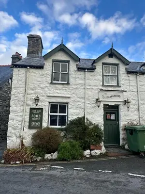 a white building with a green door on a street at Little Cottage, Llwyngwril in Llwyngwril