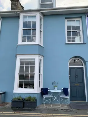 a blue house with a table in front of it at Nant Llys - Spectacularly placed with sea views in New Quay