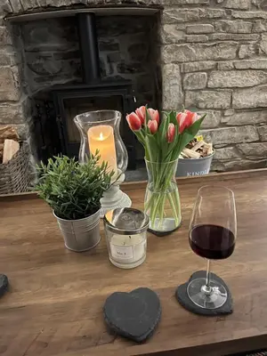 a wooden table with a glass of wine and flowers at Nant Llys - Spectacularly placed with sea views in New Quay