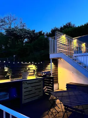 a patio with a staircase and a table and chairs at Nant Llys - Spectacularly placed with sea views in New Quay
