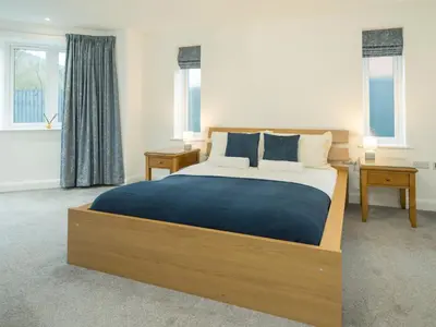 a bedroom with a large bed and two windows at Modern 4-Bed Home Spacious & Comfortable - Pass the Keys in Pontesbury
