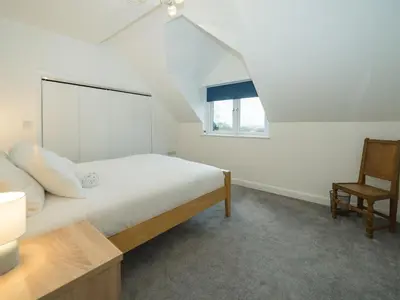 a white bedroom with a bed and a chair at Modern 4-Bed Home Spacious & Comfortable - Pass the Keys in Pontesbury