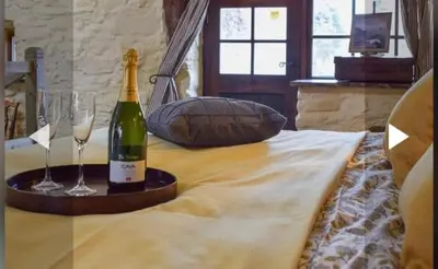 a bottle of wine and two glasses on a bed at Glovers cottage private hot tub and super king in Llanrhystyd
