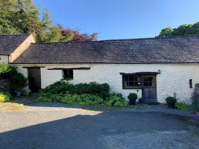 a white brick house with a black roof at Glovers cottage private hot tub and super king in Llanrhystyd