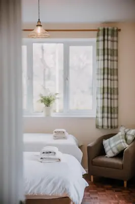 a room with two beds and a chair and a window at The Pantry in Erwood