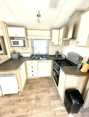 a kitchen with white cabinets and a stove top oven at Gold Standard Luxury and Modern Static Caravan at Clarach Bay in Aberystwyth