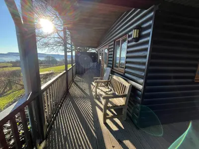 a porch with a wooden bench on a balcony at Red Kite Lodge in Clyro