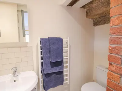 a bathroom with a blue towel hanging on the wall at Millstone Cottages - Granary Cottage in Shrewsbury