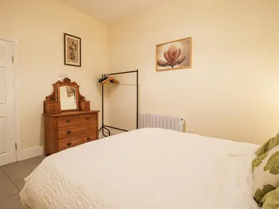 a bedroom with a white bed and a dresser at Millstone Cottages - Middle Cottage in Shrewsbury