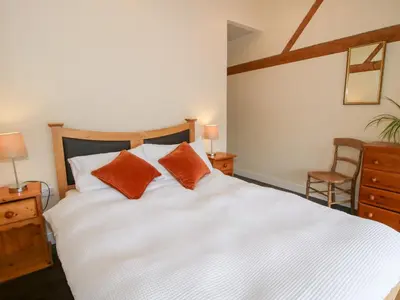 a bedroom with a white bed with two orange pillows at Millstone Cottages - Breidden View in Shrewsbury