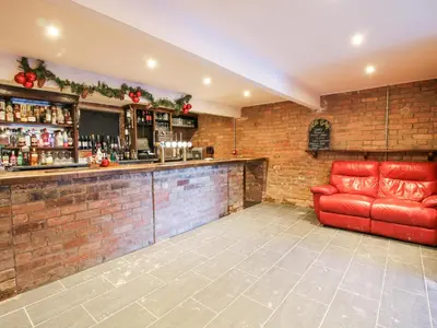 a bar with a red couch in a room at Millstone Cottages - Breidden View in Shrewsbury