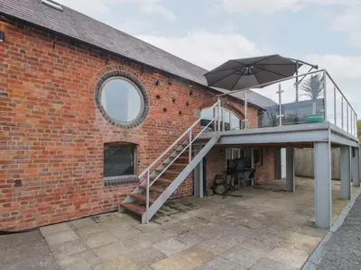 a brick building with a staircase and an umbrella at Millstone Cottages - Breidden View in Shrewsbury
