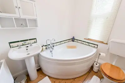 a bathroom with a large white tub and a sink at The Old Vicarage with hot-tub & sauna in Vowchurch