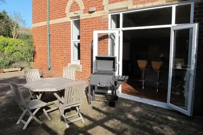 a patio with a table and chairs and a grill at The Old Vicarage with hot-tub & sauna in Vowchurch