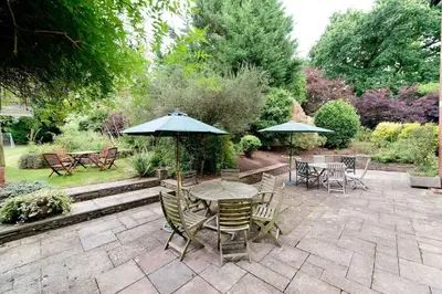 a patio with tables and chairs and umbrellas at The Old Vicarage with hot-tub & sauna in Vowchurch