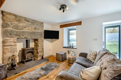 a living room with a stone fireplace and a couch at 2 Bed in Penmaenpool oc-m30050 in Arthog